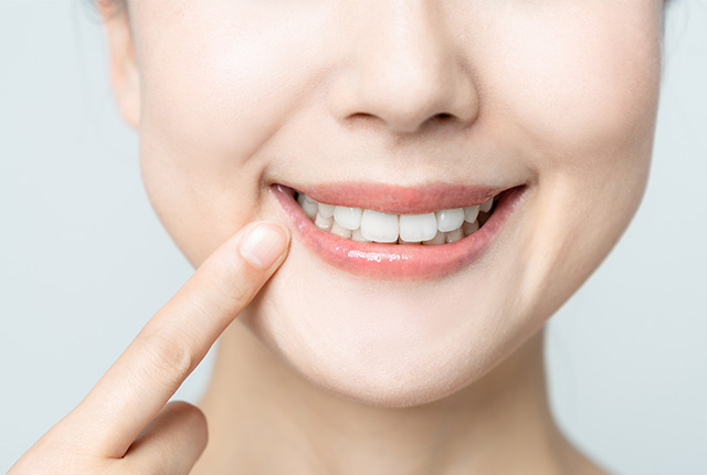 歯を見せて笑う女性の口元